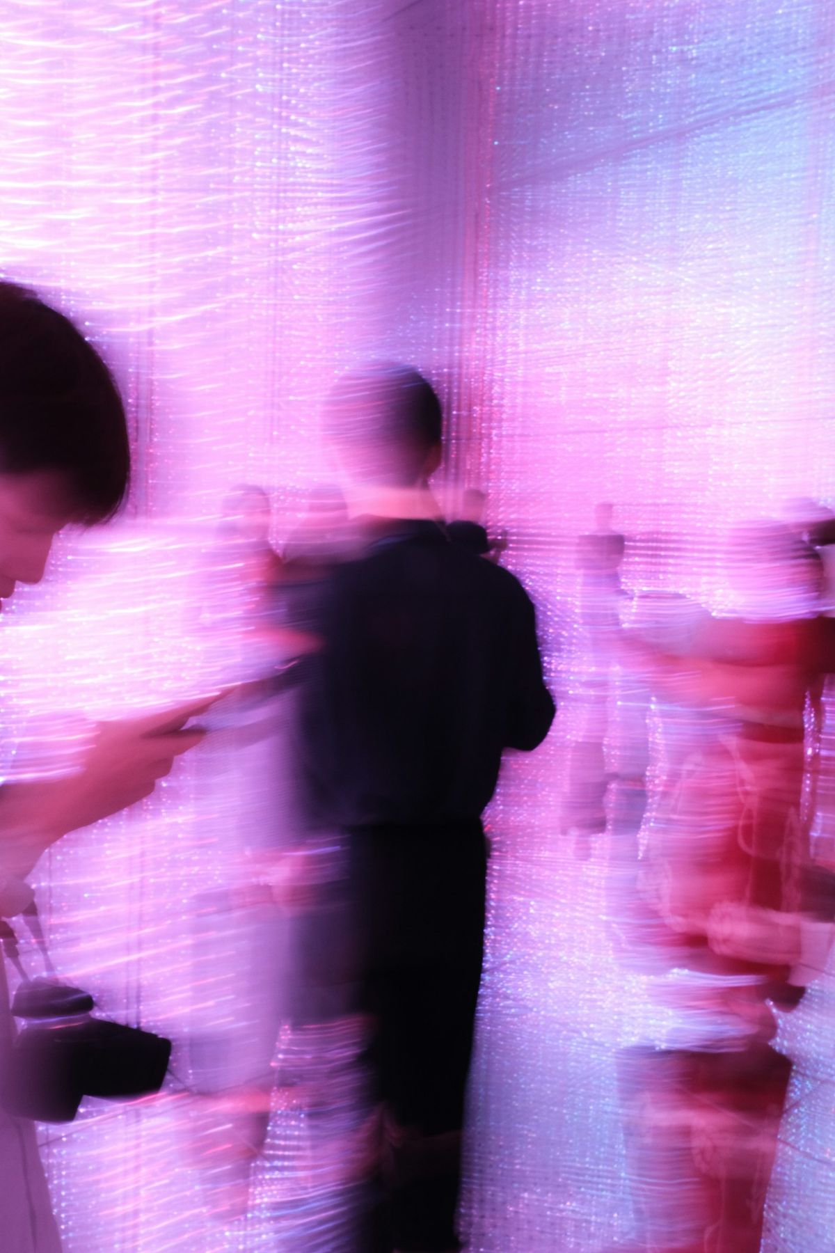 Visitors move through a glowing pink light space